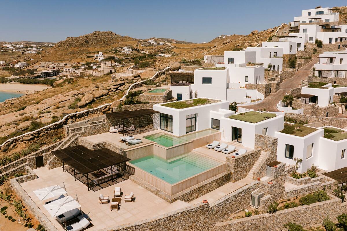 A modern resort with white buildings, a rooftop pool, and a view of the surrounding landscape.