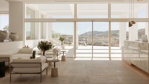 A spacious, modern interior with large windows offering a view of the landscape. - Cali Mykonos (Mykonos)