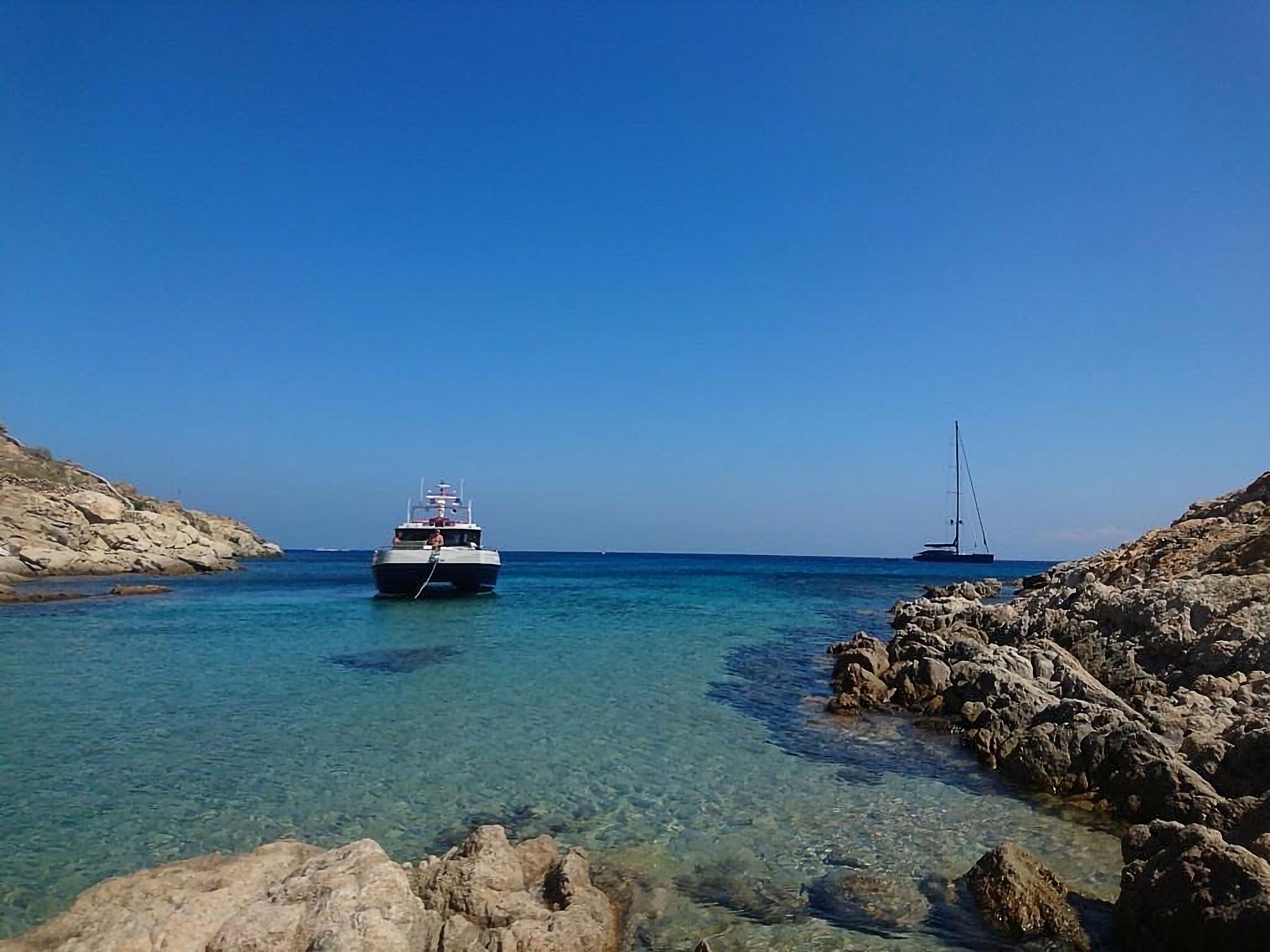 A boat anchored near rocky shores with clear water.