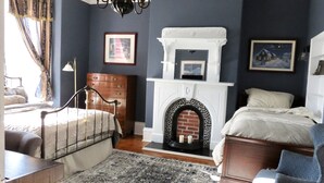 A bedroom with a bed, dresser, and fireplace. - The Roses Heritage Inn (St. John's)
