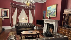 A traditional living room with a fireplace, leather sofas, and classic decor. - The Roses Heritage Inn (St. John's)