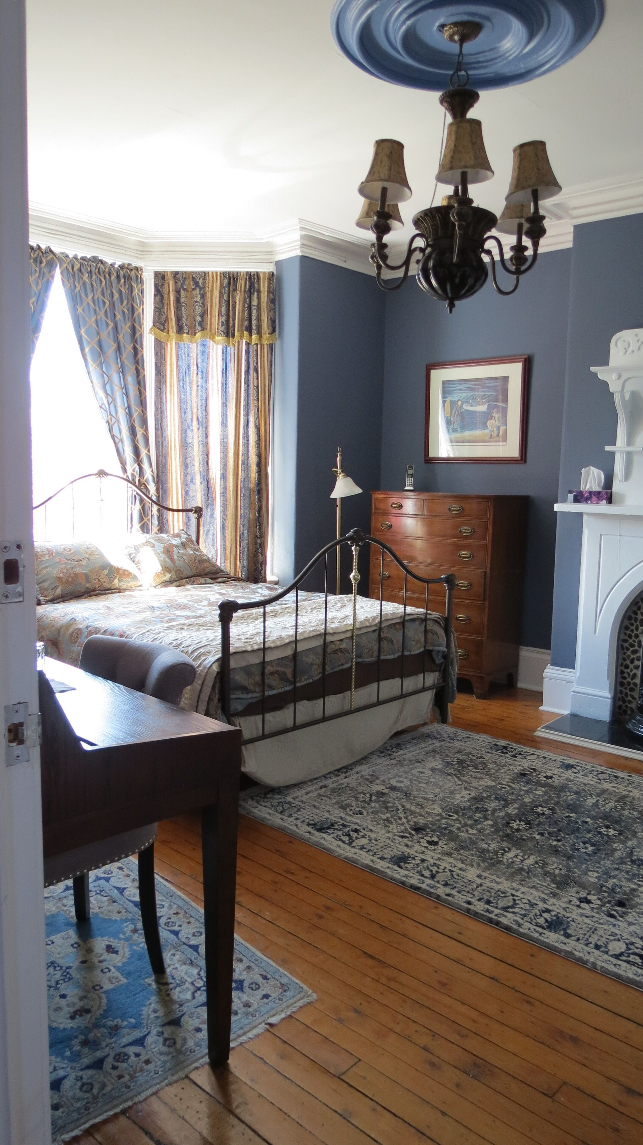 A bedroom with a bed, dresser, and a chandelier.