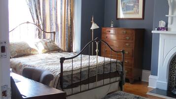 A bedroom with a bed, dresser, and a chandelier.