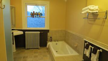 A bathroom with a bathtub, a window with a view of birds, a towel rack, and a radiator.