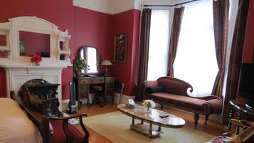 A traditional room with a fireplace, a sofa, a table, and a mirror.