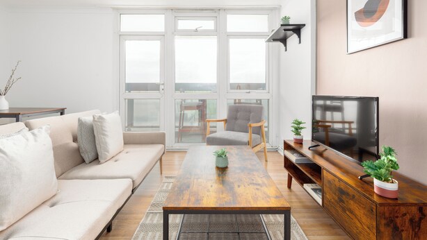 A modern living room with a sofa, a coffee table, a TV, and a large window.