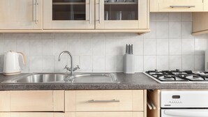 A kitchen with a stainless steel sink, a gas stove, and wooden cabinets.