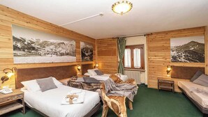 A hotel room with two beds, wooden walls, and mountain landscape pictures. - Hotel Gran Baita (Sauze d'Oulx)
