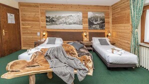 Una habitación con dos camas, paredes de madera y dos cuadros en la pared.