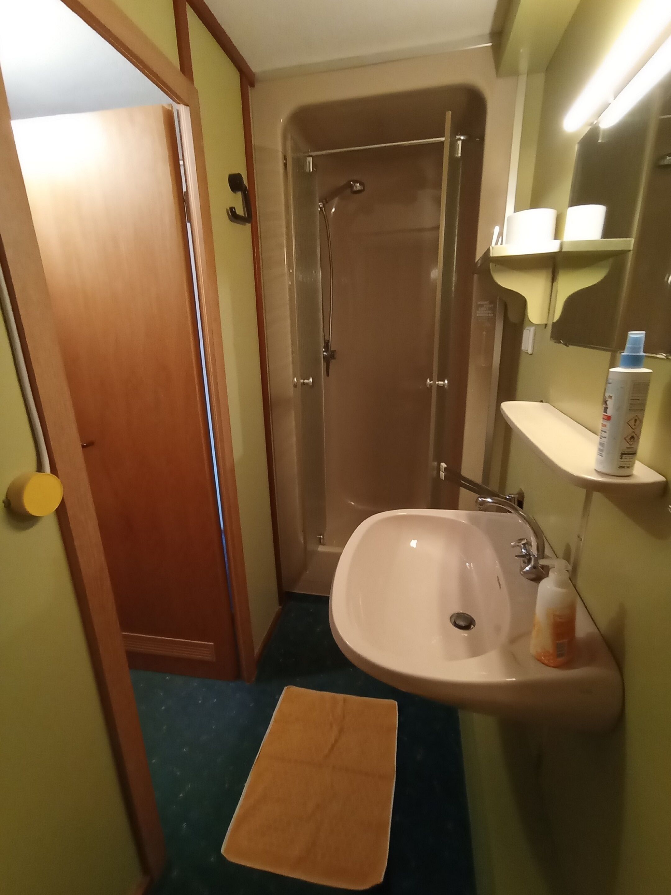 Un baño con ducha, lavamanos y una toalla en el suelo.