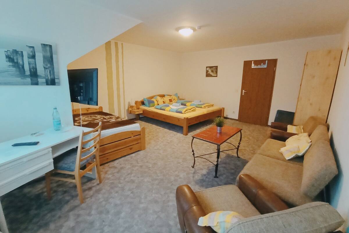 Una habitación acogedora con una cama, un escritorio, una silla, un sofá y una pequeña mesa con una planta.
