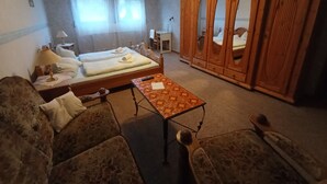 Ett rum med två sängar, en garderob i trä, ett mönstrat bord och en soffa.