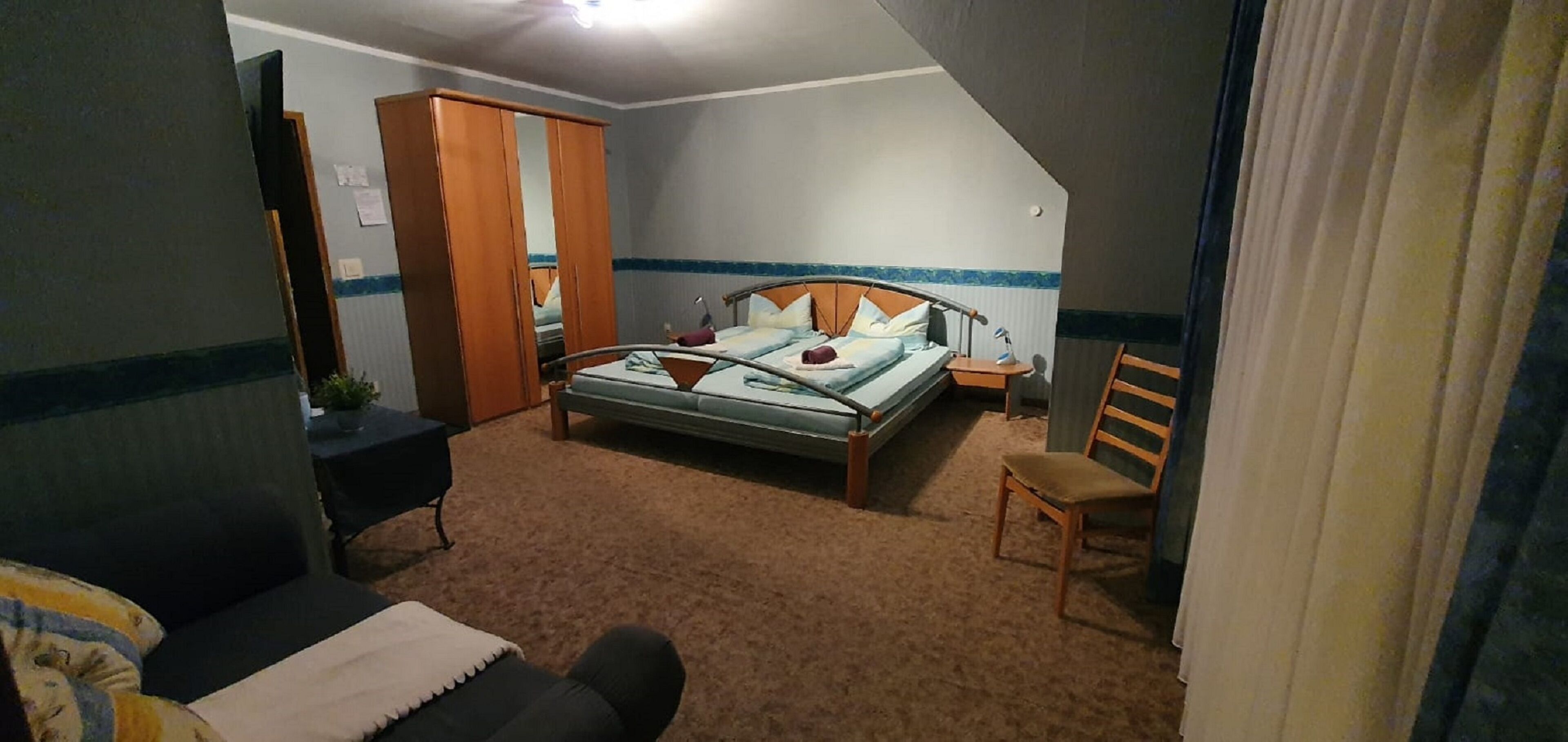 A bedroom with a bed, a chair, a wardrobe, and a desk.