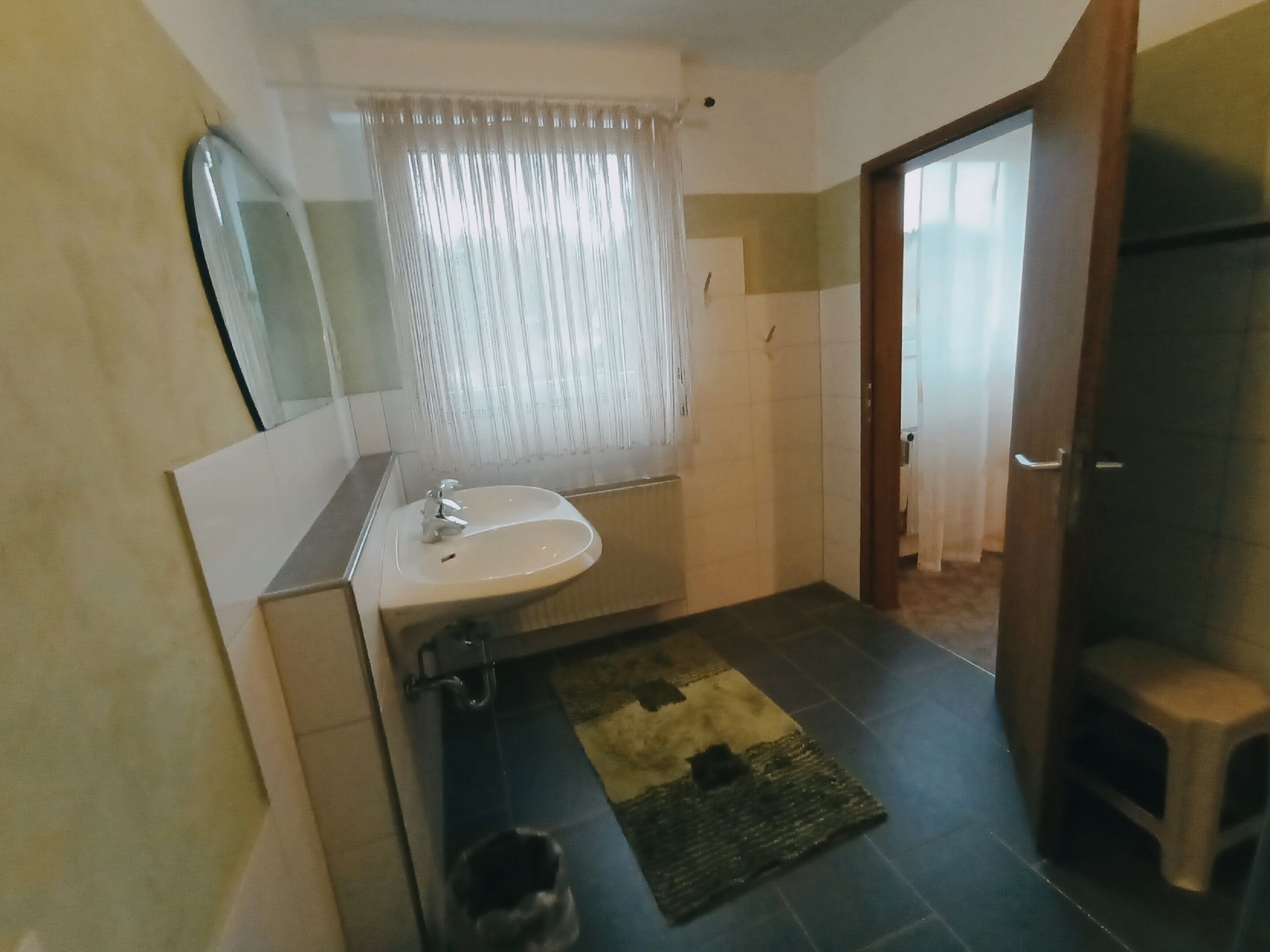 A bathroom with a sink, mirror, and a shower area.