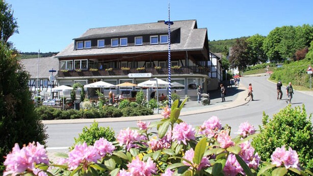 En traditionell byggnad med en balkong, utomhusmöbler och en klar himmel.