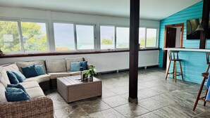 Amplia sala de estar con un ventanal, un conjunto de sofás, una mesa de centro y una zona de bar.