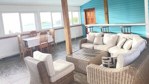 Un patio cubierto con mobiliario de mimbre, una mesa y sillas.