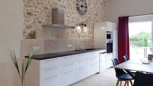 A modern kitchen with a stone wall, a clock, and a dining area with a table and chairs.