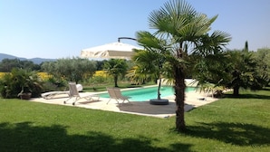 A pool area with lounge chairs, a palm tree, and a building in the background.