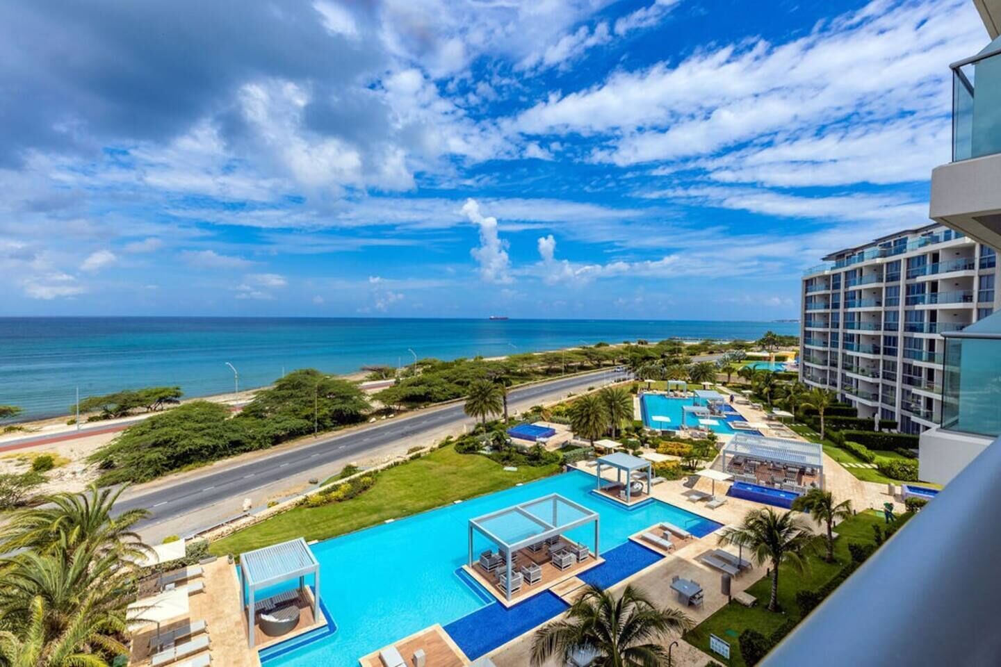 Ein Resort mit mehreren Schwimmbecken, einer Straße und Blick auf den Ozean.