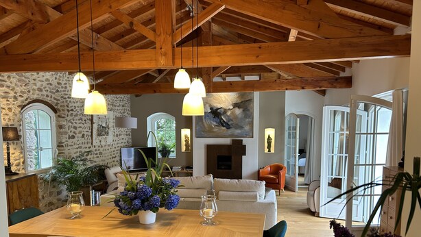 A spacious living area with a wooden dining table, blue chairs, and a stone wall. - In a green setting, very nice house . (Arcangues)