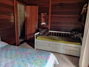 Ein Zimmer in einer Holzhütte mit einem Bett, einem kleinen Tisch und einer Tür.