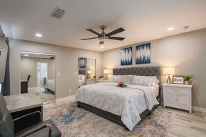 A bedroom with a bed, bedside tables, a ceiling fan, and artwork on the wall. - Group Friendly 6 BR Pool Compound Near Windsor (Lake Havasu City)