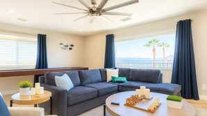 Ein modernes Wohnzimmer mit einem Ecksofa, einem runden Couchtisch und einem Deckenventilator.