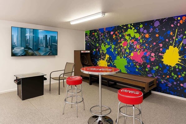 A modern office space with a cityscape painting, a colorful abstract wall, and a Coca-Cola branded table and stools.