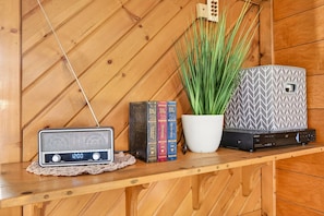 Un estante de madera con una radio antigua, una planta en maceta y un dispositivo Sony.