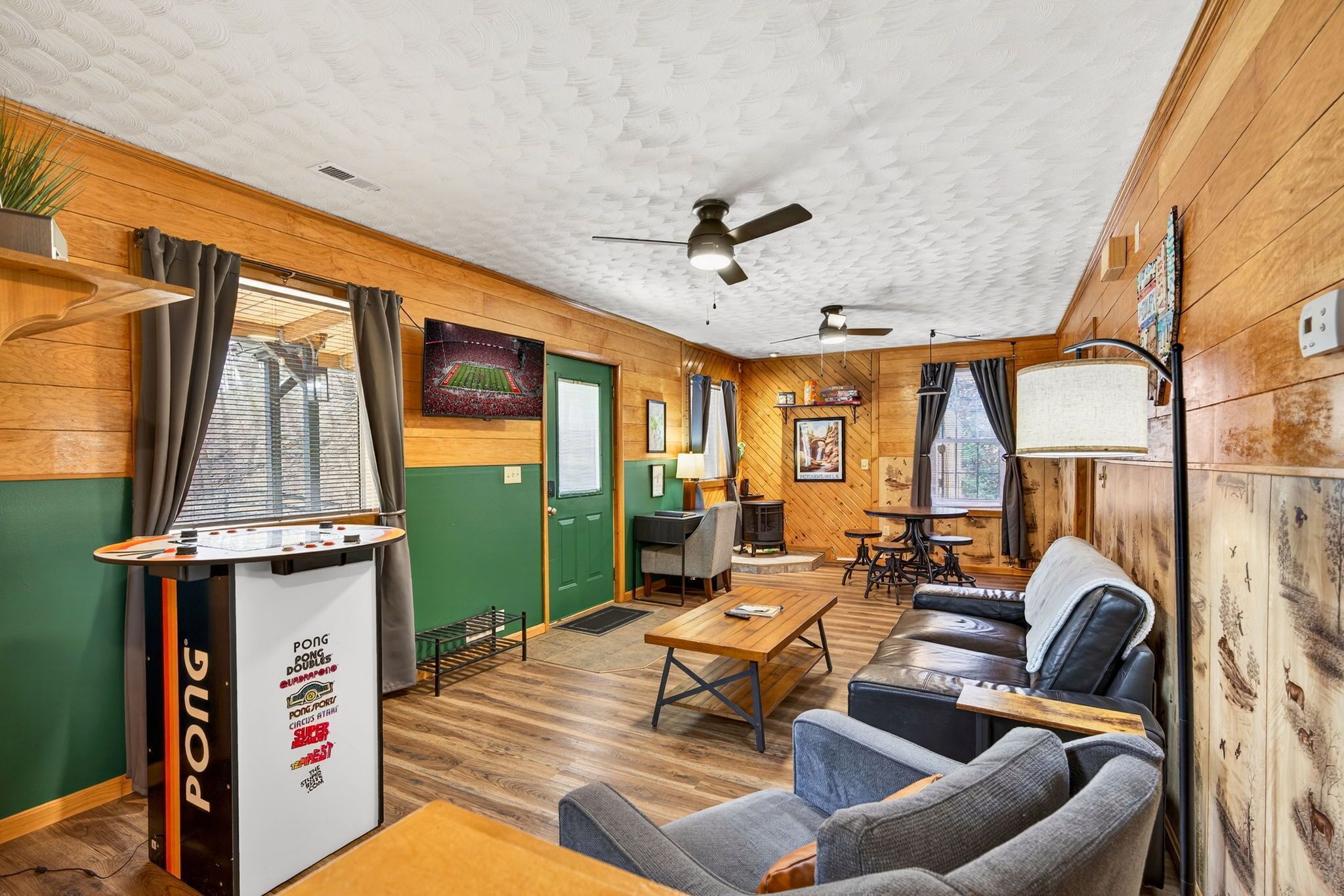 A cozy room with a ping pong table, a sofa, a coffee table, a desk, and a chair.