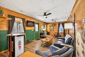 Ein gemütliches Zimmer mit Tischtennisplatte, einer Couch, einem Couchtisch, einem Schreibtisch und einem Stuhl.