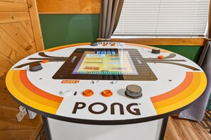 Una mesa de pong con marcador digital, perillas de control y un rótulo con la marca 'PONG'.