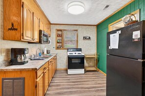 A kitchen with wooden cabinets, a stove, a refrigerator, and a microwave.
