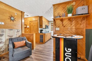 Una cocina moderna con armarios de madera, una isla central y una zona de estar con sofá gris.