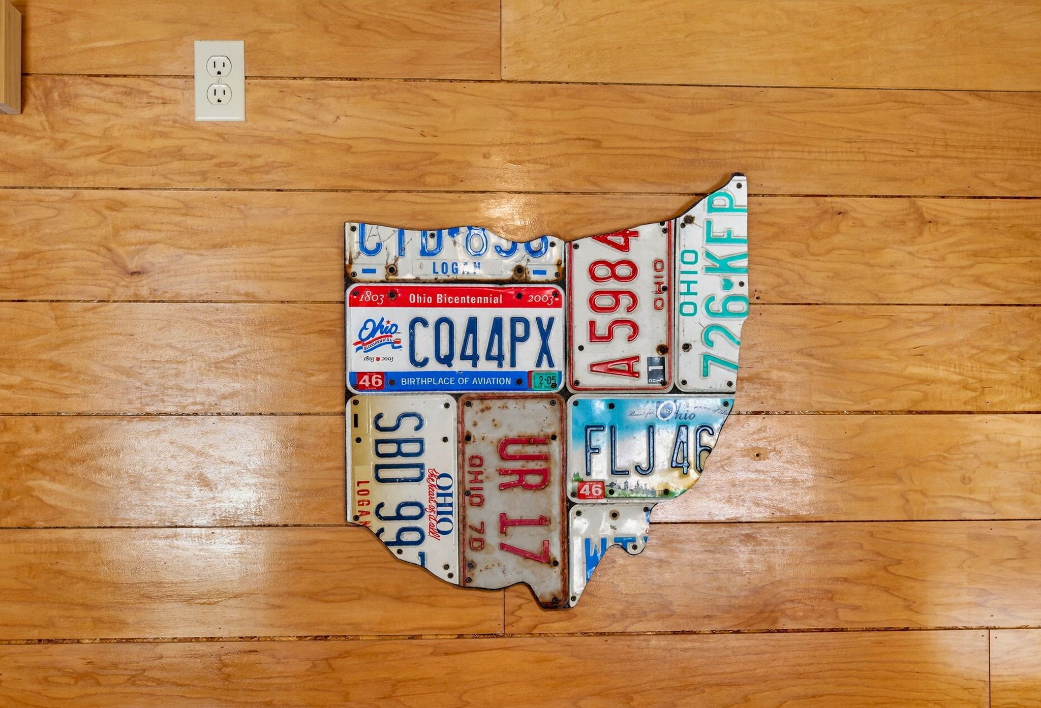 A wooden floor with a collection of Ohio license plates arranged in the shape of the state's outline.
