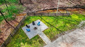 Un espacio al aire libre con zona de estar y un brasero, rodeado por un piso de grava y una valla de madera.