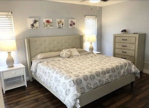 Un dormitorio con cama, mesitas de noche, cómoda y decoración en la pared.