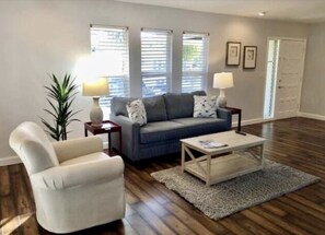 Una sala de estar con sofá, sillón, mesa de centro y dos lámparas.