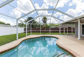 Piscina al aire libre techada con borde curvo, rodeada por una valla blanca y una terraza de madera.