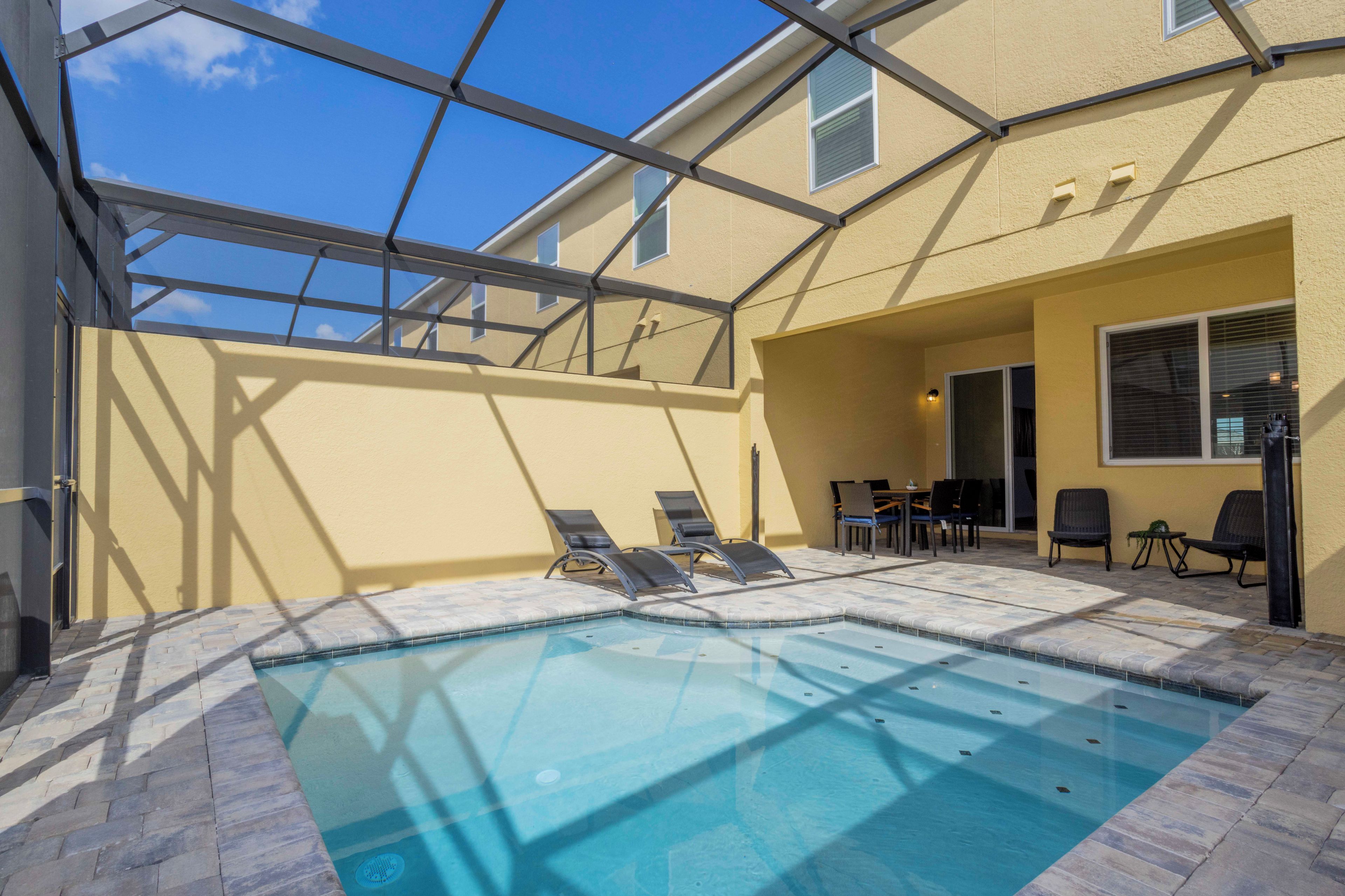 An outdoor swimming pool with lounge chairs and a covered patio area.