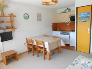A compact kitchen with a dining table, chairs, a microwave, and a stove.