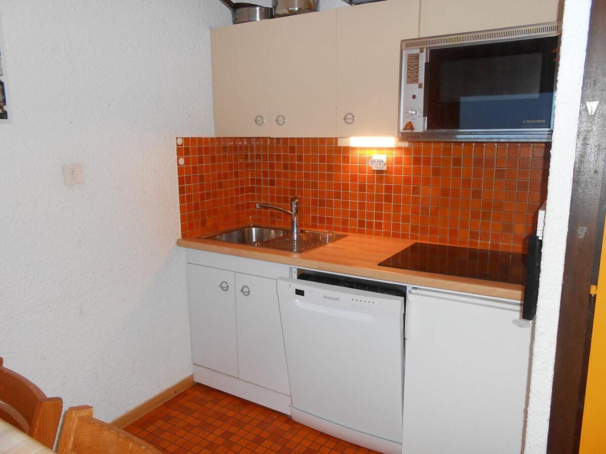 A compact kitchen with a sink, dishwasher, and microwave.