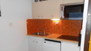 Eine kleine Küche mit Spüle, Geschirrspüler und Mikrowelle.