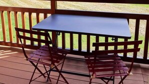 A wooden deck with a table and chairs overlooking a mountainous landscape. - 100m from resort center, 4th floor, view mountain, balcony, parking, tv, ski locker, 40m² (Les Deux Alpes)