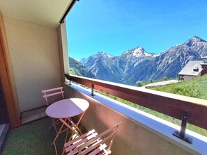 A balcony with a table and chairs, offering a mountain view.