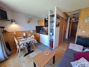 A compact living space with a dining area, kitchenette, and a sofa.