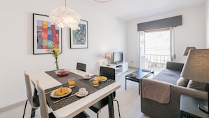 A modern hotel room with a dining area, a sofa, a TV, and artwork on the walls. - LAGOS CLASSIC by HOMING (Lagos)