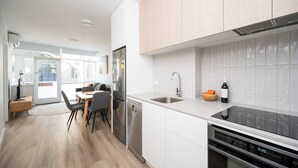 Een moderne keuken met witte kasten, een roestvrijstalen koelkast, een vaatwasser en een zwart inductiekookplaat.