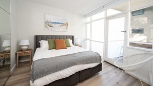 Een slaapkamer met een groot bed, een nachtkastje, een stoel en een raam met uitzicht.